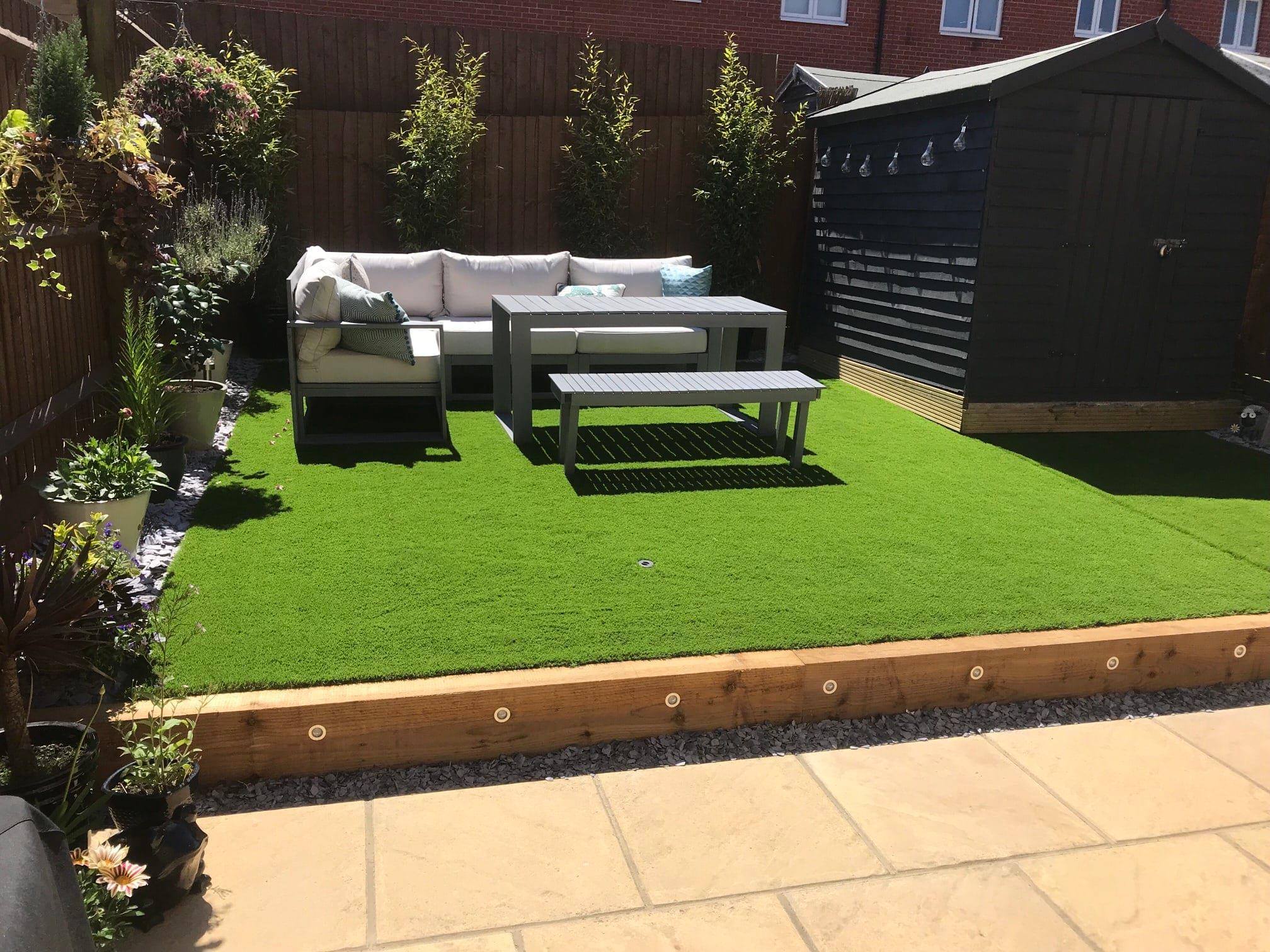 Completed Landscaping Project in East London with an outdoor corner sofa on a raised artificial grass area with LED underlighting
